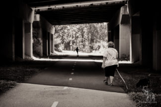 Mother walking dog approaches son silhouetted in the distance, bike path