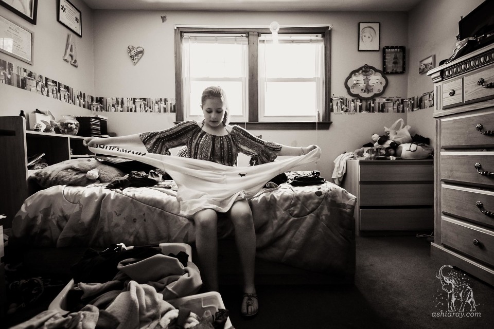 teen girl in bedroom sorting laundry